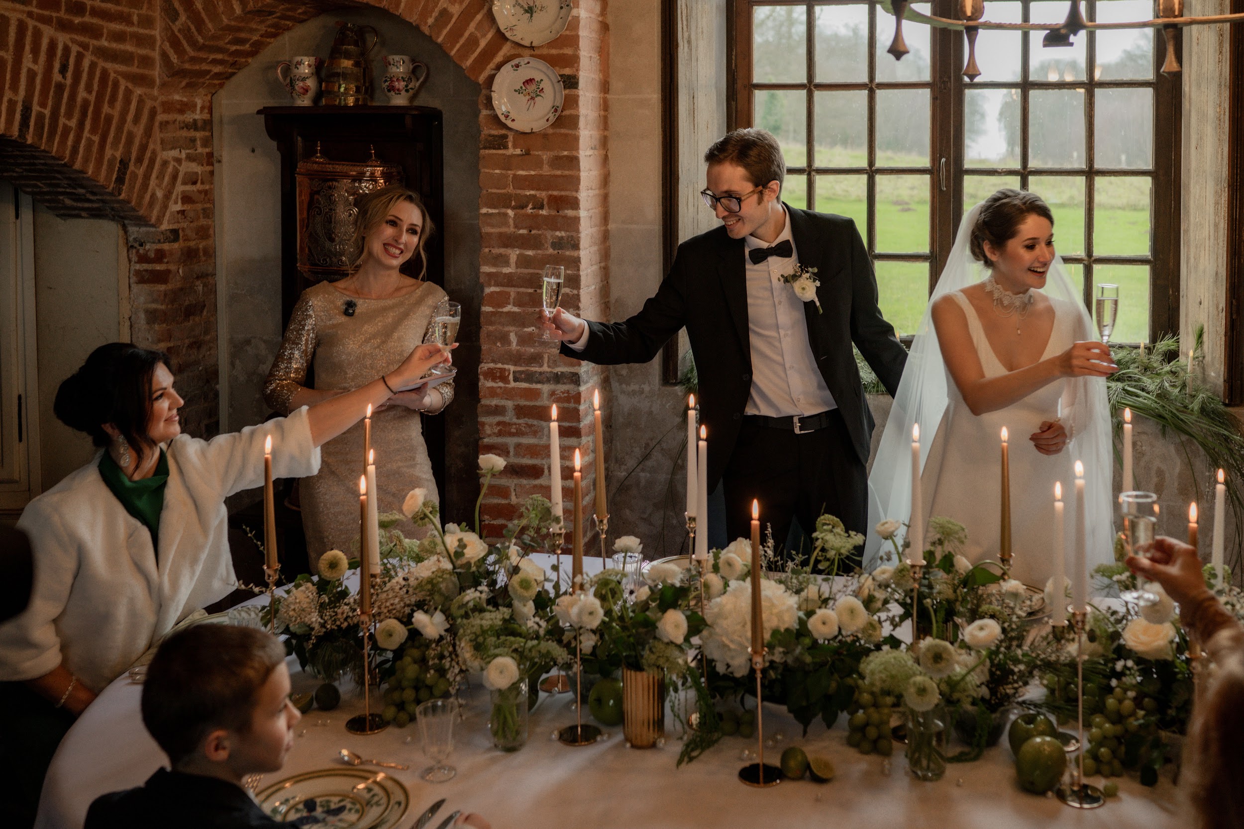 The newlyweds and guests raising a toast at the candlelit dinner table at Château de Bonnemare